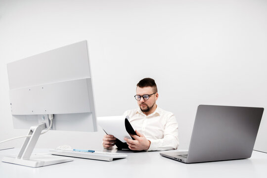 A businessman at a computer in an office, analyzing stock market and inflation charts, sorting through papers. The concept is to capture the tense decision-making process in times of economic instabil - Powered by Adobe
