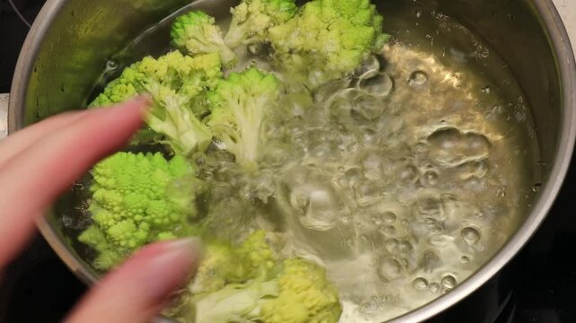 green romanesco broccoli florets boiling in water in a pot. Close-up of vegetable cooking in boiling water for a healthy recipe or meal preparation
