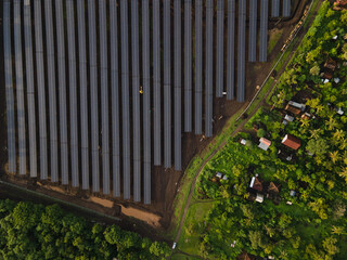 Aerial View of Large Solar Power Plant with Electrical Substation in Green Landscape.