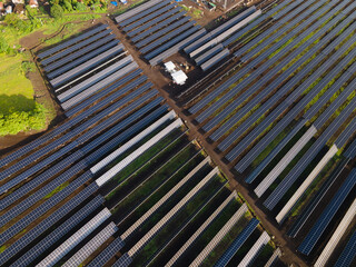 Obraz premium Aerial View of Large Solar Power Plant with Electrical Substation in Green Landscape.