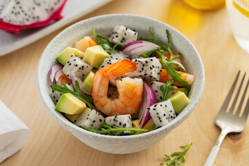 Delicious exotic salad with pitahaya, shrimp, avocado, red onion and arugula in a bowl. Dietary low-calorie food. Close up