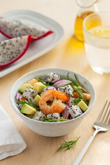 Healthy exotic salad with pitahaya, shrimp, avocado, arugula and red onion in a bowl. Dietary low-calorie food
