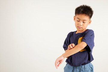 Asian little kid boy scratching itchy arm from a mosquito bite at studio shot isolated on white background, Portrait of Thai primary child dermatitis and scabies, Allergy symptoms, Malaria day concept © sorapop