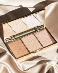 Gold highlighter makeup palette on gold silk background