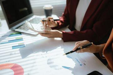 Businesswoman analyzing charts and financial data on laptop in modern office. She focuses on investment strategies and budget planning, collaborating with colleagues to drive organizational growth and