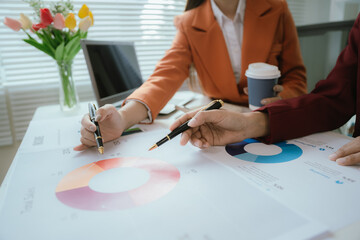 Businesswoman analyzing charts and financial data on laptop in modern office. She focuses on investment strategies and budget planning, collaborating with colleagues to drive organizational growth and