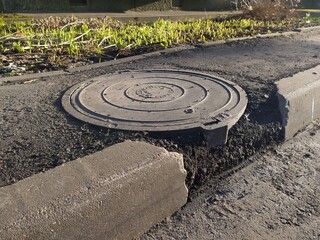 Manhole cover on the edge of the road in the city.