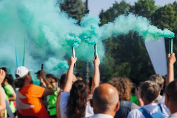 Marathon supporters crowd with coloured smoke, half-marathon in the city streets, crowd of fan...