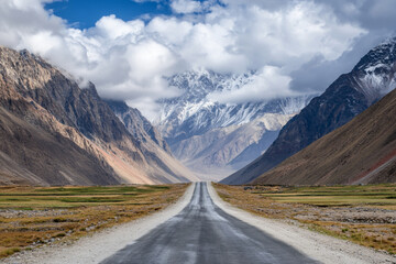 Fototapeta premium There is a long road going through a mountain valley with a mountain range in the background