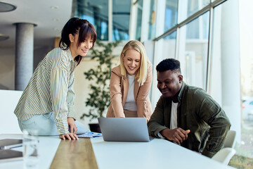 Team Collaboration Around Laptop in Modern Office Setting