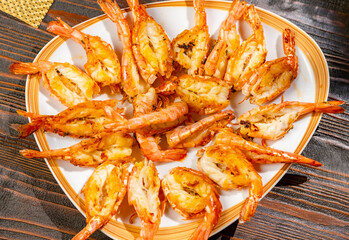 Grilled shrimps on plate on rustic wooden table close-up top view.