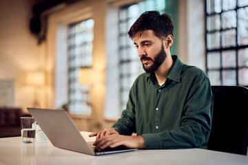 Fototapeta premium Focused Professional Working on Laptop in Modern Office Setting