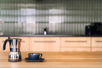 Modern kitchen setting featuring a coffee pot and cup on a wooden countertop