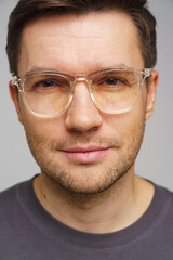 Man with clear glasses and a neutral expression poses against a plain background, showcasing a modern style