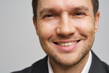 Fototapeta premium Smiling man in formal attire poses for a close-up portrait in a neutral background indoors