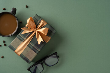 Elegant wrapped present with ribbon, sunglasses, and coffee cup on green surface