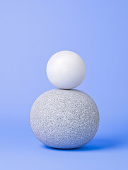Balanced grey and white spheres on a light blue background