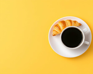 Buttery croissant beside a cup of black coffee on a yellow background