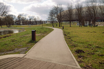 A serene view of a walking path in a park, surrounded by grass, trees, and open space. The peaceful...