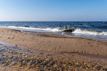 Crystal Clear Shallow Stream Merging with Ocean Waves on a Sandy Beach