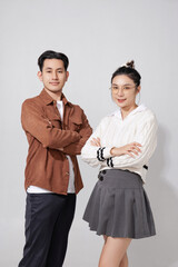 Asian cheerful young man and woman stand confidently with arms crossed, exuding positivity and teamwork on isolated studio background. Perfect for concepts like partnership, friendship, and success.