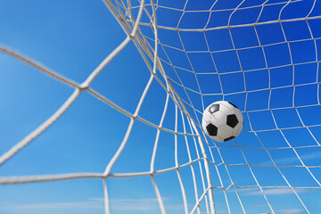  Soccer ball in soccer goal net in a big stadium isolated on blue sky. soccer net.