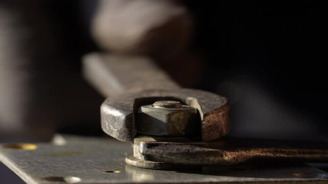 Loosening the nut using a wrench and a vise. Using old spanner wrench and clamp to remove nut from bolt, close up