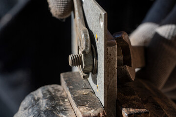 Loosening the nut using a wrench and a vise. Using old spanner wrench and clamp to remove nut from bolt, closeup