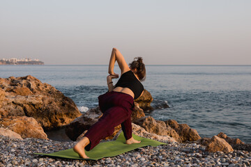 Young woman does yoga for healthy lifestyle on sea beach