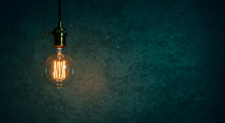 Glowing Vintage Edison Bulb Hanging Against Dark Teal Wall Background