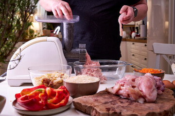 a man chops meat and vegetables in an electric meat grinder to make mincemeat for cutlets
