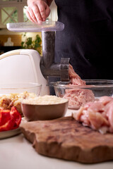 a man chops meat and vegetables in an electric meat grinder to make mincemeat for cutlets