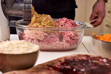 a man chops meat and vegetables in an electric meat grinder to make mincemeat for cutlets