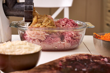 a man chops meat and vegetables in an electric meat grinder to make mincemeat for cutlets