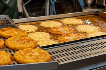 Jeon, Korean pancakes frying on a hot griddle at a market, crispy and golden brown.