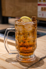 A glass of whiskey with lemon and cinnamon, on the table