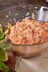 A close-up view of a glass bowl of diet chicken mince with vegetables on a white table