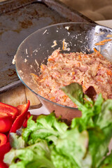 A close-up view of a glass bowl of diet chicken mince with vegetables on a white table