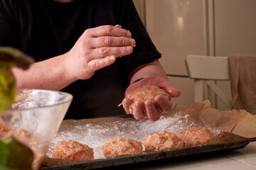 a man molds chicken meatballs and puts them on a baking tray, close up