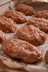 a man molds chicken meatballs and puts them on a baking tray, close up