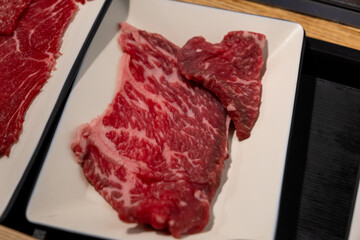 Korean Style Barbecue on plate in front of stainless grill. BBQ rare meat
