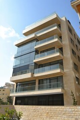 Obraz premium Modern apartment building with glass balconies in an urban setting during daylight hours, showcasing contemporary architectural design and landscaping