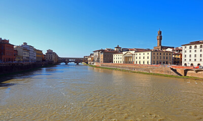 large ARNO river in Florence in central italy with the Ponte Vecchio and the tower of the Palazzo della Signoria in the background