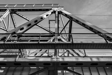 Part of the truss of the railway bridge in Moscow on the background of the sky. Black and white photo.