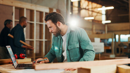 Carpenter, laptop and research with wood to measure for construction, furniture or project. Woodworker, person and plank with blueprint in creative carpentry workshop for manufacturing, art and craft