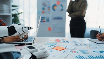 A modern office scene showcasing collaboration between human and robot, focused on data analysis and strategy development with vibrant charts and documents.Noogenesis