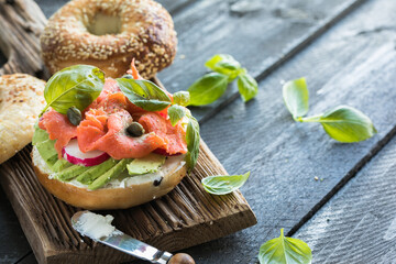 Bagel with salmon. White bagel with fish and herbs.