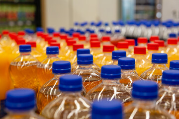 Obraz premium Assorted plastic beverage bottles with blue caps in supermarket aisle, emphasizing retail and packaging concepts
