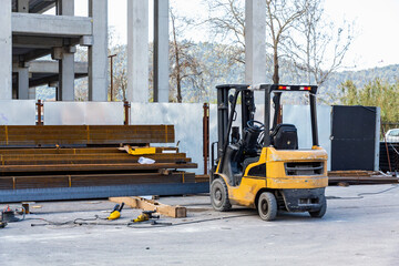 Forklift at construction site with steel beams and tools, showcasing industry equipment and outdoor work setting