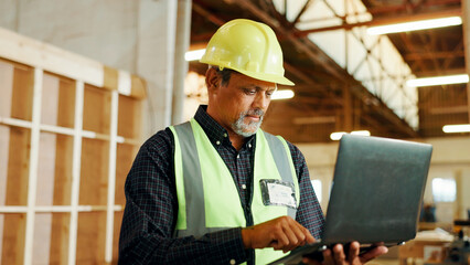 Carpentry, typing and man on laptop in workshop for woodworking, furniture restoration and lumber...